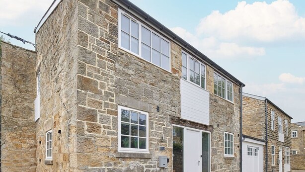A stone building with a white door and windows, a small porch, and a garage. - Host Stay 82F Galgate (Barnard Castle)