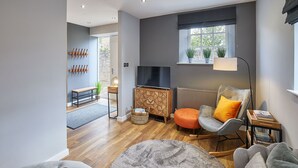A modern living room with a TV, seating, a window with plants, and a radiator. - Host Stay 82F Galgate (Barnard Castle)
