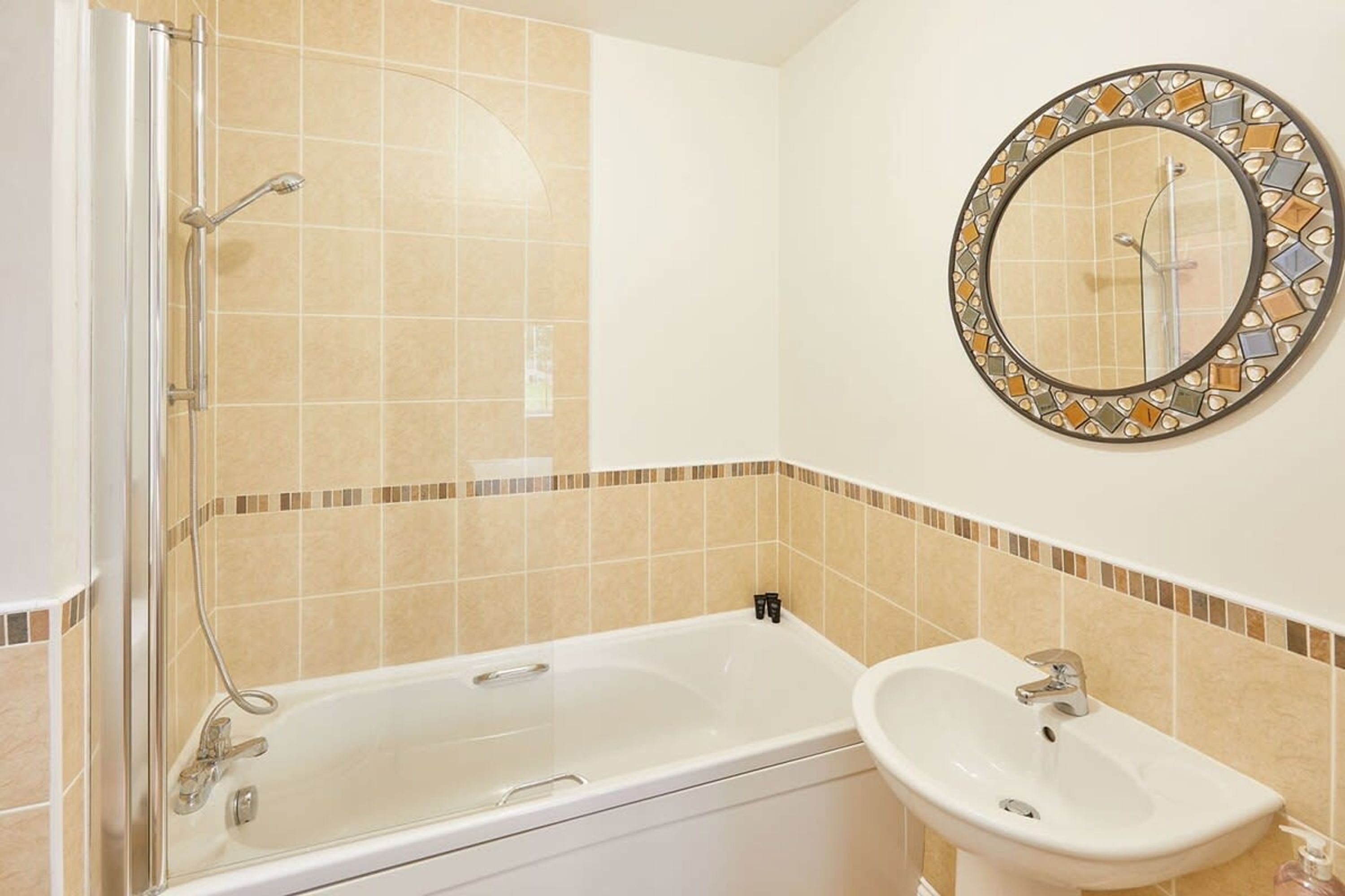 A bathroom with a glass-enclosed shower, a white bathtub, and a sink with a mirror above it.