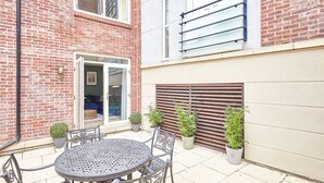 A courtyard with a round metal table and chairs, potted plants, and a sliding door. - Host Stay Turnstones Apartment (Whitby)
