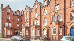 A row of red brick buildings with multiple windows and a central entrance. - Host Stay The Whitby Pearl (Whitby)
