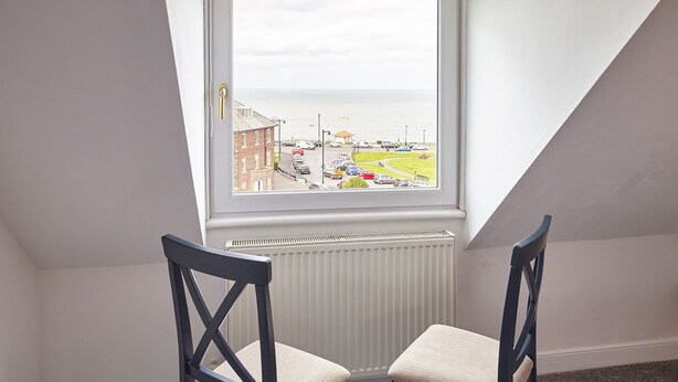 A room with a view of a parking lot and buildings across a body of water. - Host Stay The Whitby Pearl (Whitby)