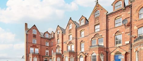 A row of red brick Victorian-style buildings with multiple windows and a blue door.