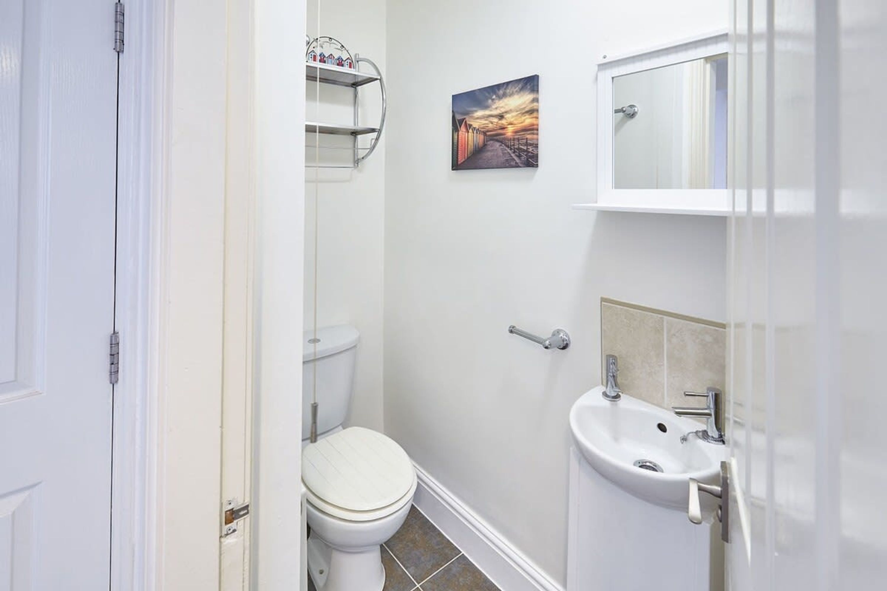 Un bagno piccolo con il water, un lavabo e uno scaffale sopra il water.