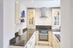 A modern kitchen with white cabinetry, a black countertop, and a built-in oven.