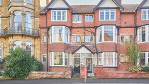 A red brick terraced house with bay windows and a white front door. - Host Stay The Lookout (Scarborough)