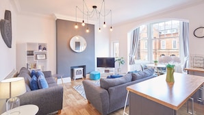 A modern living room with a sofa set, a TV, a fireplace, and a dining area with a table and chairs. - Host Stay The Lookout (Scarborough)