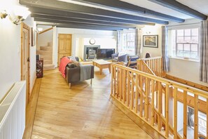 A spacious living room with a fireplace, wooden flooring, and a staircase with a wooden railing. - Host Stay Jacksons Cottage (Whitby)