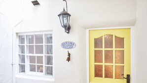 A white building with a yellow door, a window with curtains, a lantern, and a sign that reads "Jackson's Cottage". - Host Stay Jacksons Cottage (Whitby)