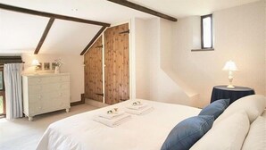 Ein Schlafzimmer mit einem großen Bett, einem Schminktisch, einem Nachttisch und einer Holztür.