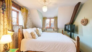 A bedroom with a large bed, a television, and a window with curtains. - Host Stay Oldcorn Cottage (Whitby)