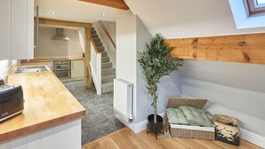 A modern kitchen with a wooden countertop, a radiator, and a staircase leading to an upper level. - Host Stay Sleepers No 8 (Pickering)