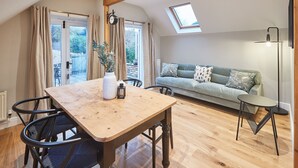 A cozy living room with a wooden dining table, a sofa, and a skylight. - Host Stay Sleepers No 8 (Pickering)