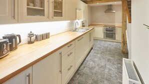 A modern kitchen with a wooden countertop, stainless steel appliances, and light-colored cabinetry. - Host Stay Sleepers No 8 (Pickering)