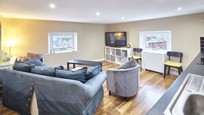 A modern living room with a sofa, armchair, and a TV on a stand. - Host Stay Abbey Heights (Whitby)