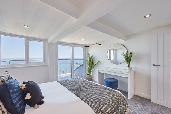A bedroom with a large bed, a fireplace, and a view of the sea. - Host Stay Penthouse Pier View (Whitby)
