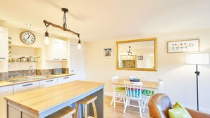 A modern kitchen with a wooden island, white cabinets, and a clock on the wall. - Host Stay The Old Dairy (Ripon)