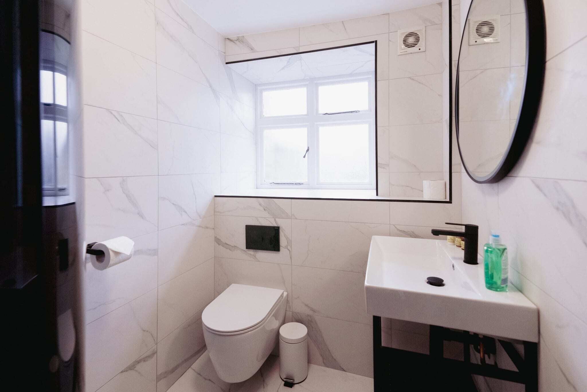 Une petite salle de bain comprenant des toilettes, un lavabo, un miroir et une fenêtre.