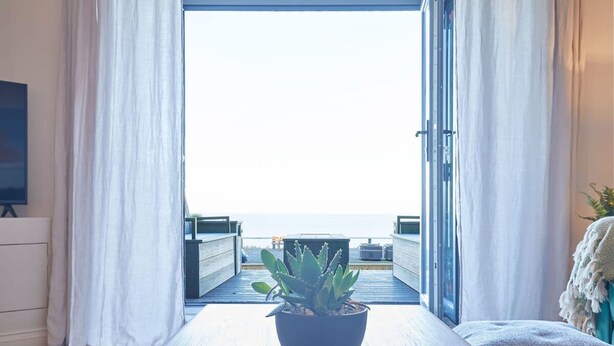 Ein Zimmer mit großem Fenster, einem Blumentopf und Meerblick.
