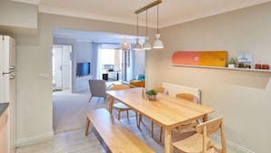 Eine moderne Küche mit Holztisch und Bank, einer Pendelleuchte und Blick in den Wohnbereich.