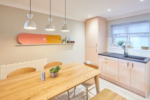 A modern kitchen with pendant lighting, a wooden dining table, and a built-in oven.