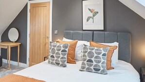A bedroom with a bed, pillows, a bedside table, a chair, a door, and a framed picture on the wall. - Host Stay Uggleby House Briggswath (Whitby)