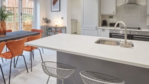 A modern kitchen with a large island, bar stools, and a skylight. - Host Stay Uggleby House Briggswath (Whitby)