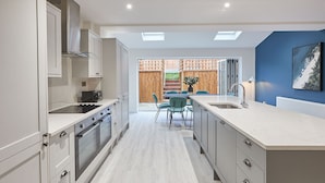 A modern kitchen with a central island, built-in oven, and a dining area with a table and chairs. - Host Stay Iburn House Briggswath (Whitby)