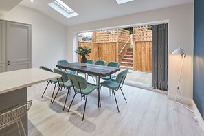 A modern kitchen with a dining area, featuring a large table, chairs, and a skylight.