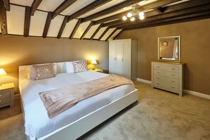 A bedroom with a large bed, a wardrobe, a dresser, and a mirror.