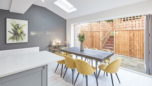 A modern kitchen with a grey countertop, a dark wooden dining table, and yellow chairs. - Host Stay Littlebeck House Briggswath (Whitby)