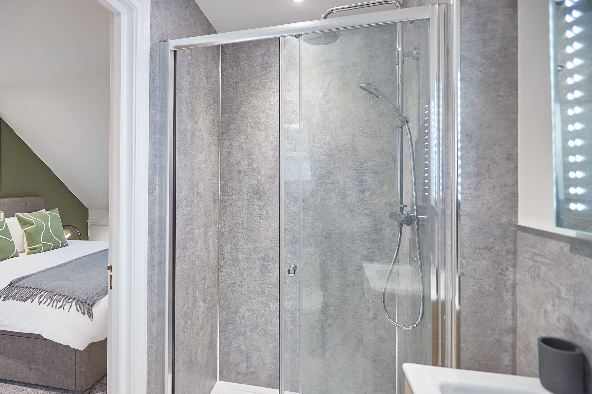 A modern bathroom with a glass-enclosed shower, a white sink, and a mirror with lights.