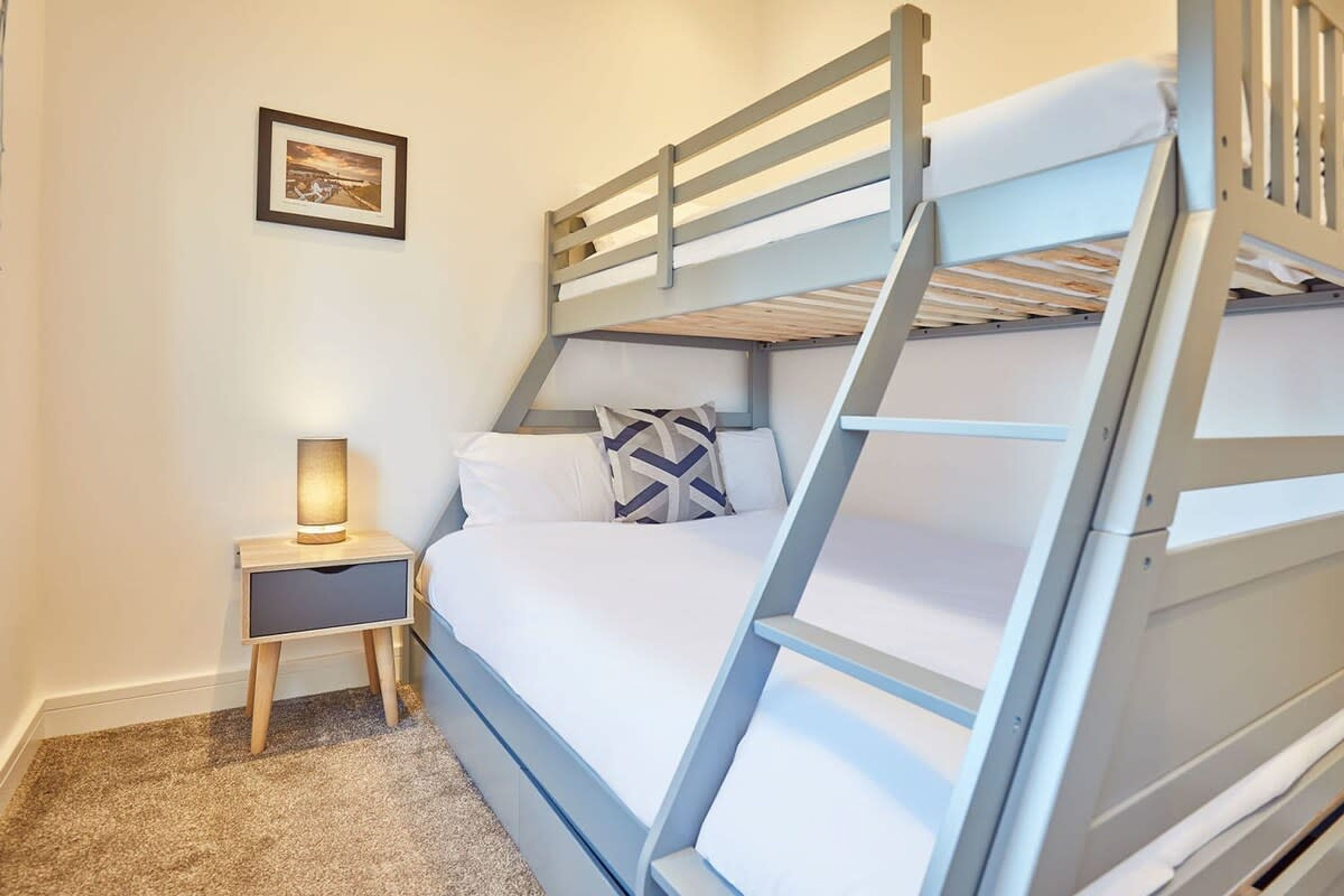 A bunk bed with a nightstand and a lamp.