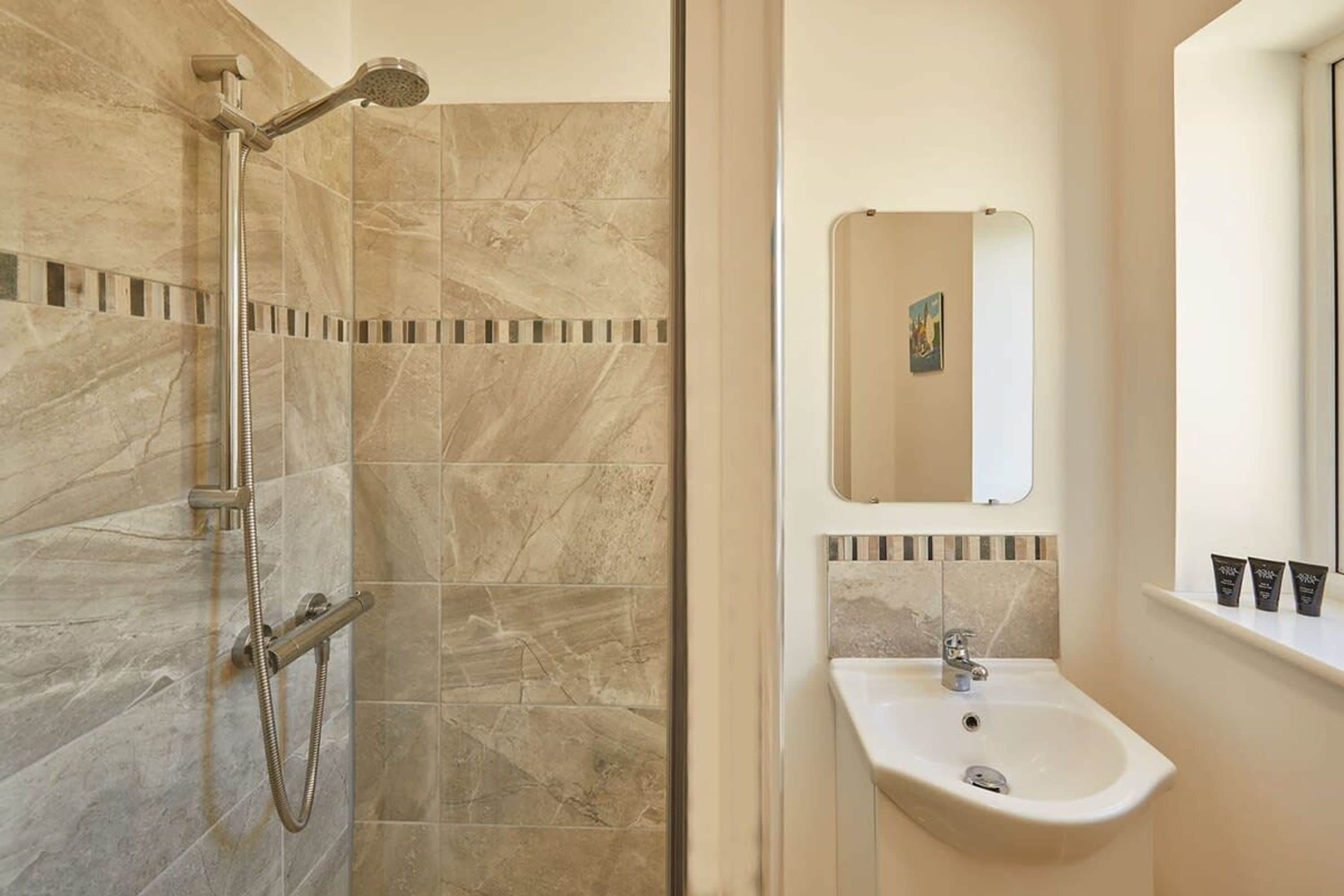 A bathroom with a shower, sink, and mirror.