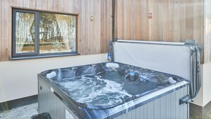 A hot tub with a wooden exterior, a window with a view of trees, and a light fixture on the wall. - Host Stay The Parlour (Newcastle-upon-Tyne)