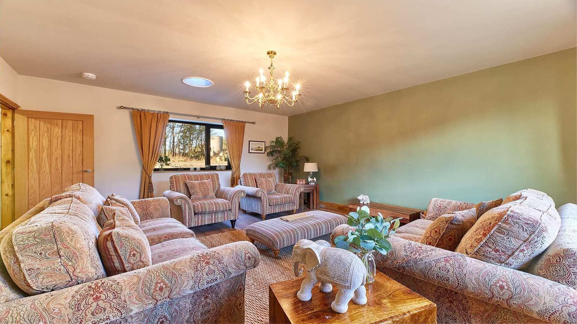 A living room with patterned sofas, a wooden coffee table, and a chandelier.