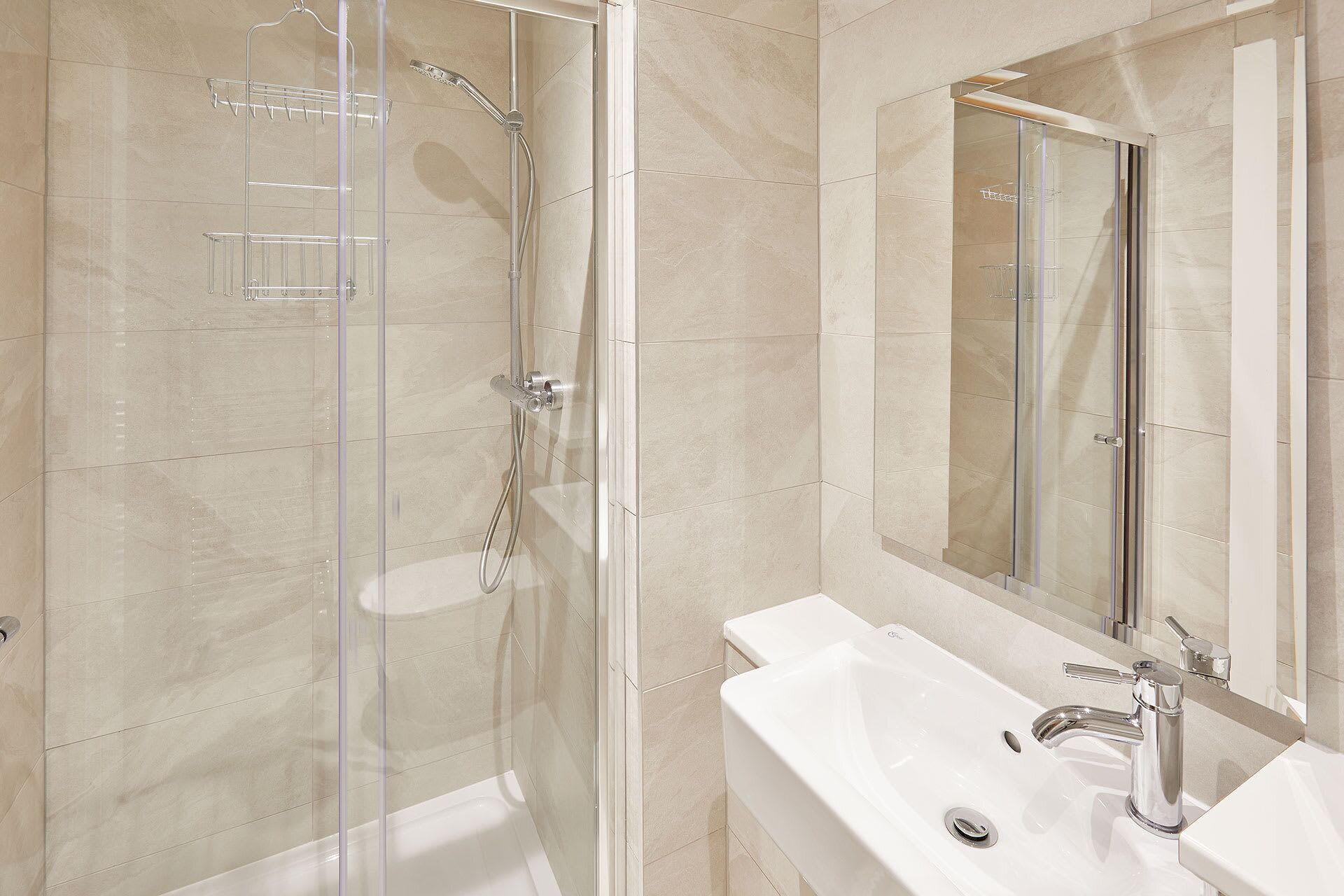 A modern bathroom with a glass-enclosed shower, a white sink, and a large mirror.