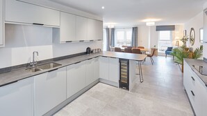 A modern kitchen with white cabinetry, a built-in island, and a dining area with a table and chairs.