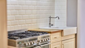 A kitchen with a gas stove, oven, and a sink with a faucet. - Host Stay Harbour Mist Cottage (Whitby)