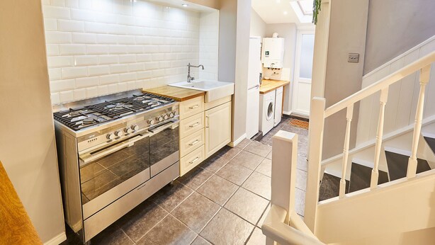 A kitchen with a gas stove, a sink, and a built-in oven. - Host Stay Harbour Mist Cottage (Whitby)