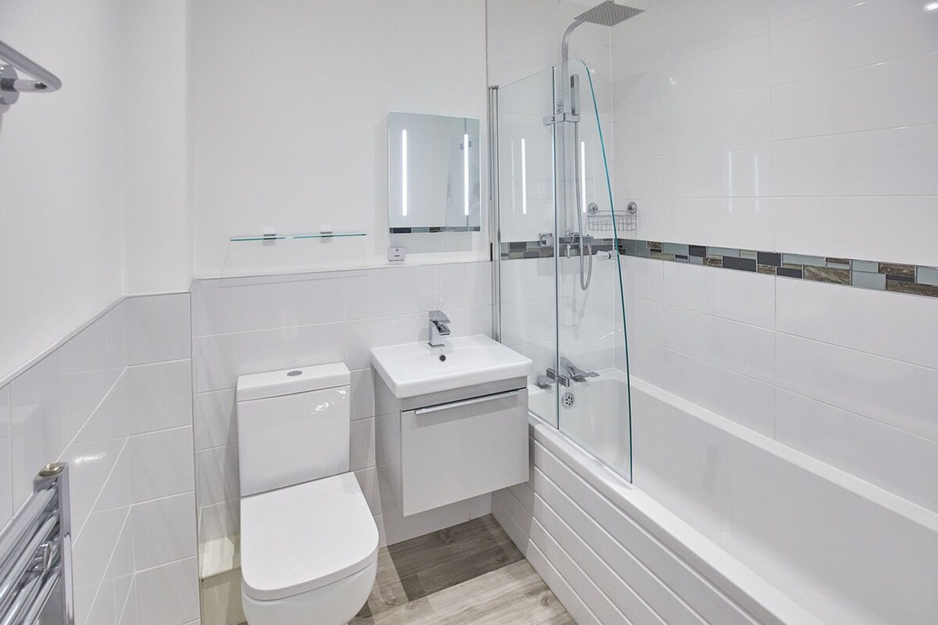 A modern bathroom with a toilet, sink, and glass-enclosed shower.