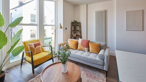 A modern living room with a sofa, yellow armchair, and a round wooden table. - Host Stay Abbey Nook (Whitby)