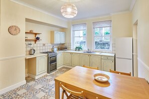 Kitchen features a central island, stove, oven, sink, and dining table.