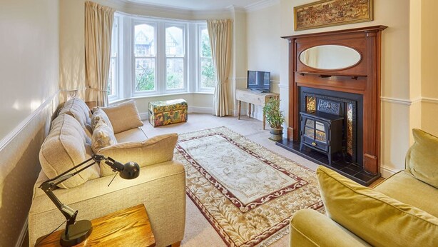 A living room with a sofa, armchair, and a fireplace. - Host Stay The Garden Flat (Scarborough)