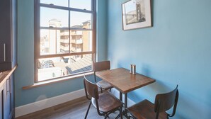 A room with a wooden table and four chairs, a window with a view of buildings, and a framed picture on the wall. - Host Stay Turnstone (Saltburn-by-the-Sea)