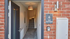 A hallway leading to a door with a number plate indicating "4 Jet Cottage." - Host Stay Jet Cottage Spa Well (Whitby)