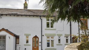 A white building with a tiled roof, a wooden front door, and multiple windows. - Host Stay Cummins Goings Cottage (Barnard Castle)