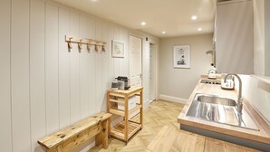 A compact kitchen with a wooden bench, a small table, and a sink. - Host Stay The Salt Nook (Whitby)