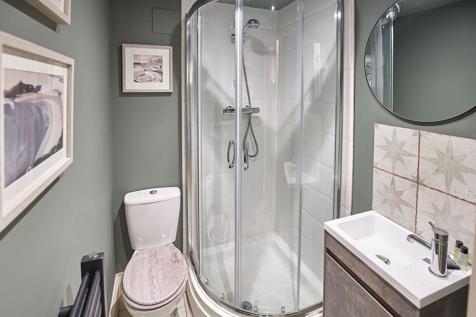 Een moderne badkamer met een douchecabine van glas, een toilet en een wastafel met spiegel.