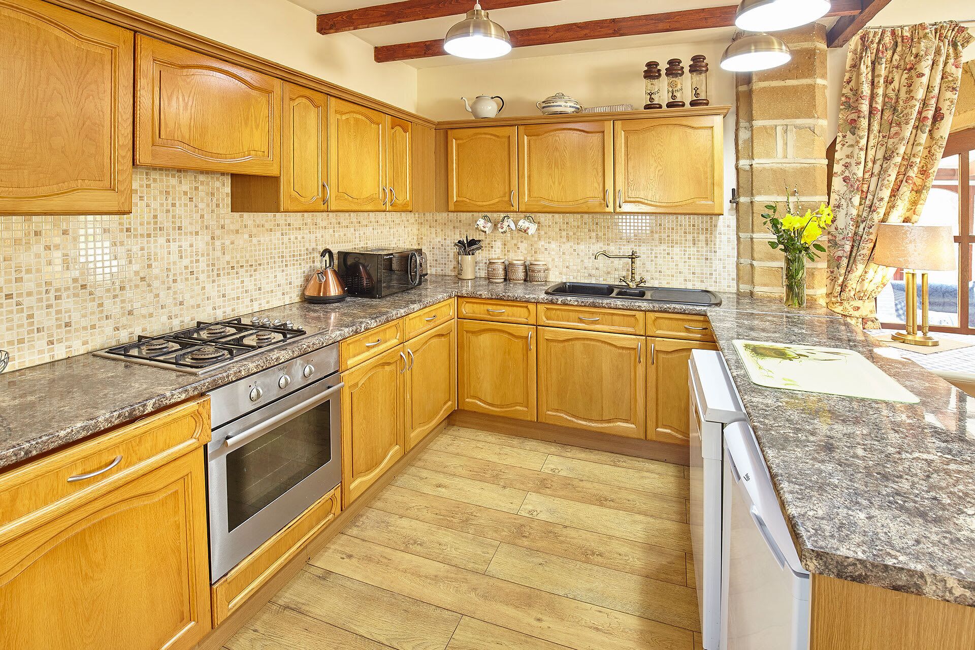 A kitchen with wooden cabinets, a granite countertop, a stove, an oven, and a dishwasher.